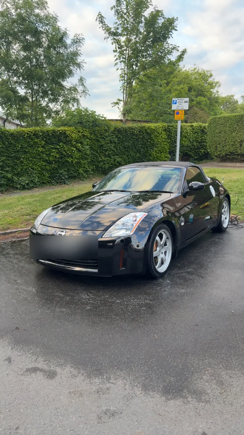 Freshly washed black convertible with a deep wet-look shine, number plate blurred