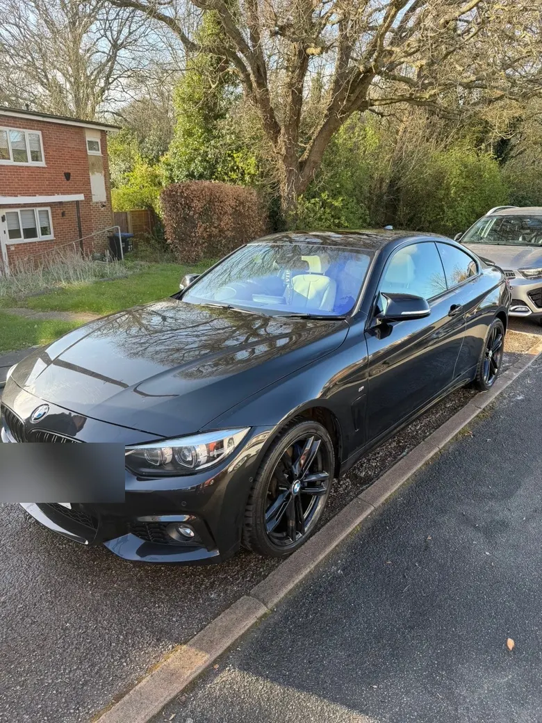 Freshly corrected black coupe parked on a residential driveway, number plate blurred