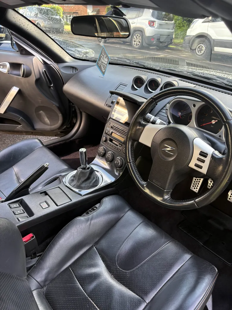 Cleaned 350Z cabin shot from the passenger side - black leather seats, centre console and steering wheel